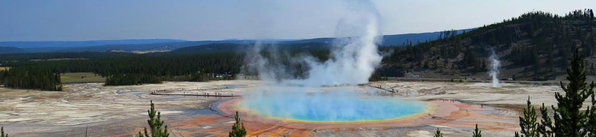 Water emitting steam in the middle of a mountainous landscape